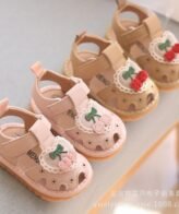 صندل أطفال صغير وناعم يتميز بتصميم لطيف مع زخرفة كرز مطرزة على مقدمة الحذاء محاطة بدانتيل صغير، تحتوي على لاصق فيلكرو لسهولة الارتداء والخلع